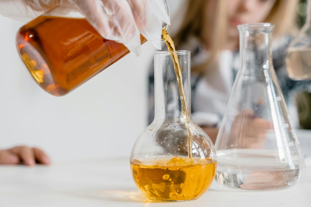 pexels-photo-8471799-8471799 A curious child pours liquid into a flask during a science experiment indoors.